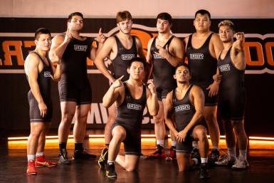 Eight members of the Doane wrestling team pose on the practice mats in Butler Gymnasium.